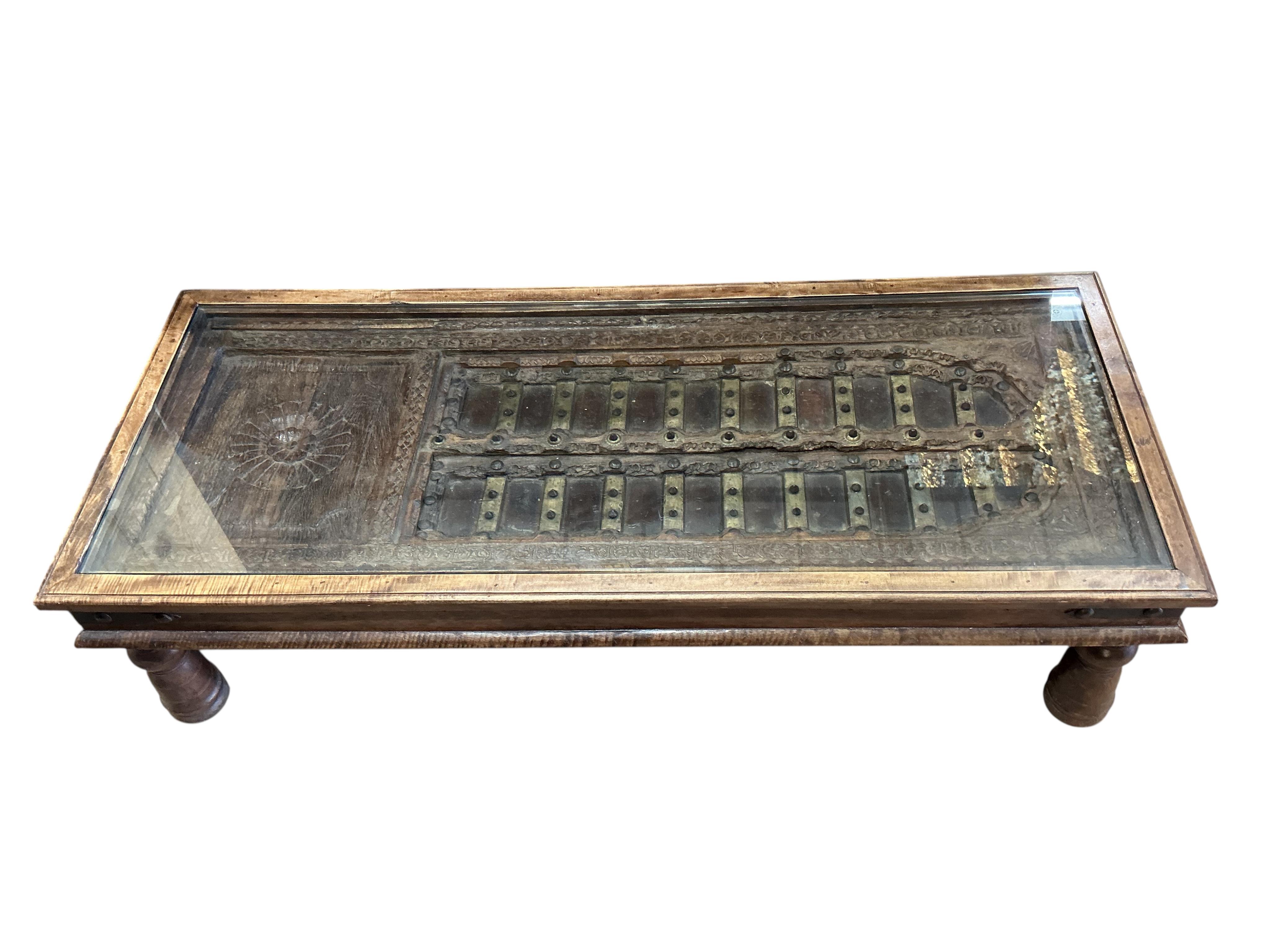 A 19th century brass mounted Indian door, now as a coffee table, width 154cm, depth 64cm, height 40cm